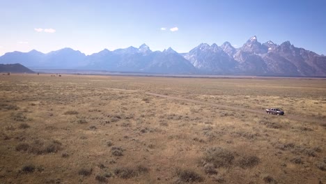 drone shot of the grand teton national park with the tetons visible and the grasslands brilliant below