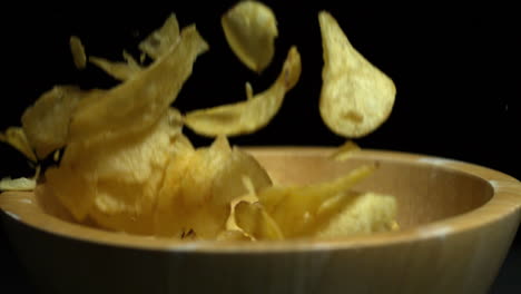 potato chips falling into wooden bowl