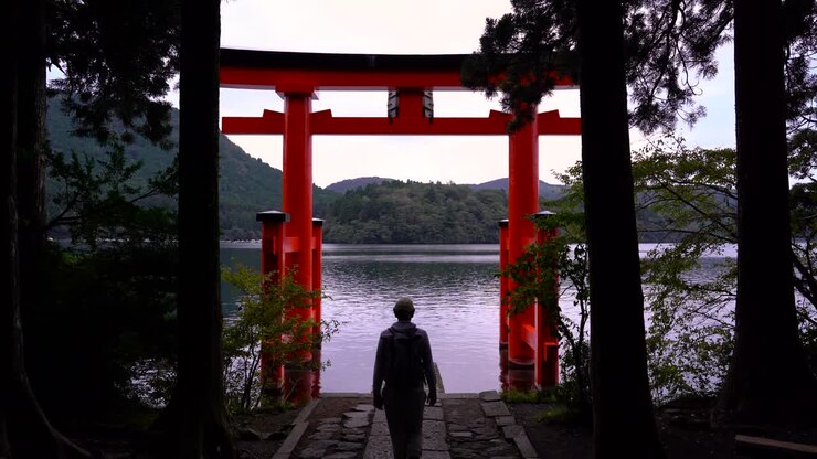 Escursionista uomo che cammina verso il famoso cancello rosso Torii al Santuario di Hakone vicino a Tokyo.