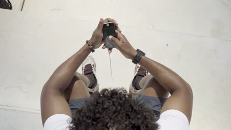 vista superior de un hombre afroamericano usando un teléfono moderno al aire libre.