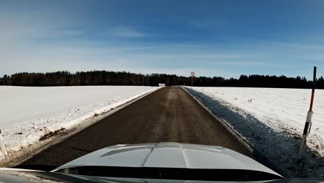 Hyperlapse-of-driving-a-car-fast-through-a-winter-landscape,-leading-through-a-snow-covered-forest-at-a-fantastic-day-at-the-winter-season