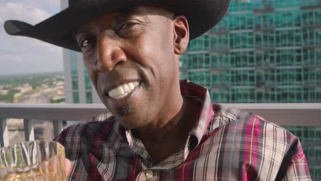 retrato de un hombre negro con sombrero de vaquero sosteniendo un vaso de tiro