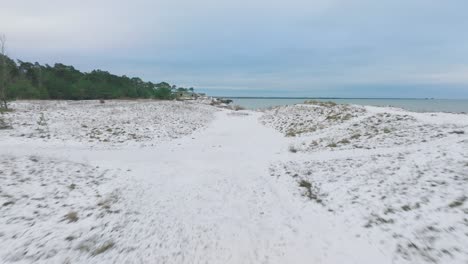 aerial establishing view of abandoned seaside fortification buildings at karosta northern forts on the beach of baltic sea , overcast winter day, wide drone shot moving forward