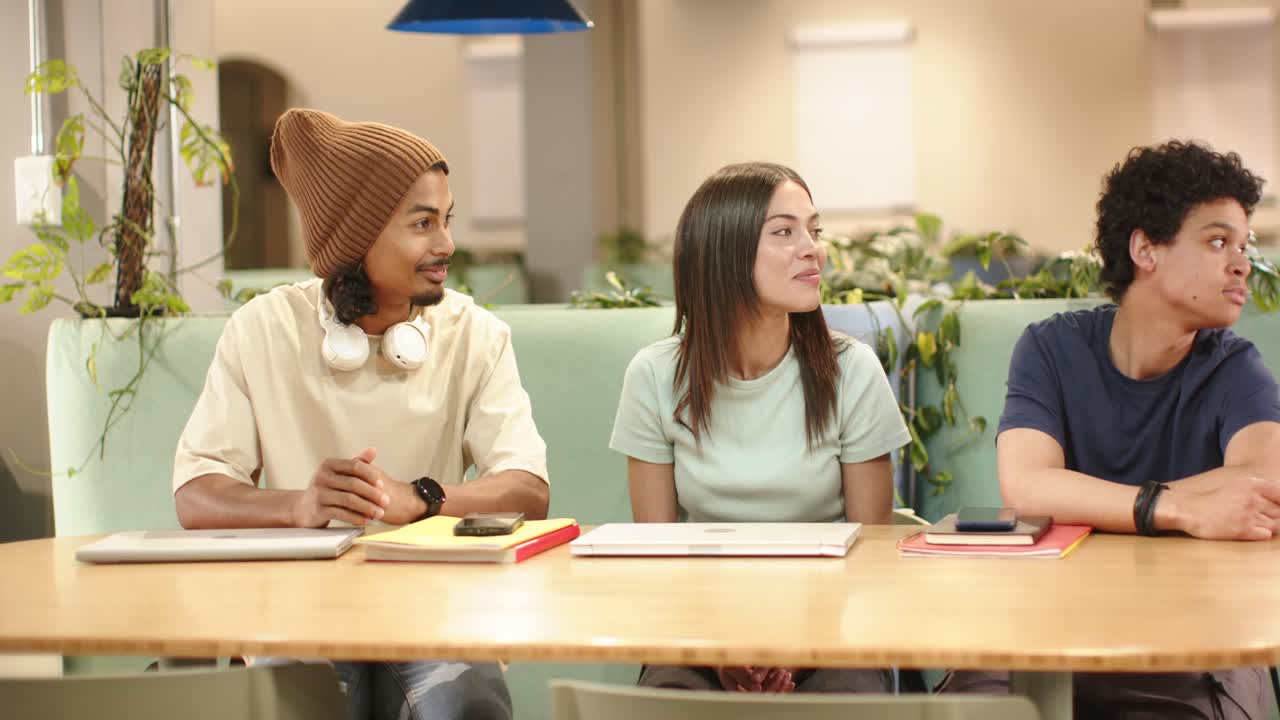 Teman Afrika-Amerika di meja belajar menyadari gerakan kiri, menoleh dan tersenyum ke laptop