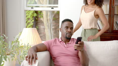 couple relaxing on sofa, woman hugging man from behind, enjoying quality time