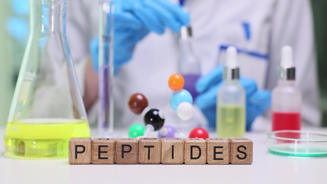 Ahşap küpler, laboratuvar masasında cam eşyaların yanında peptidler kelimesini heceleyerek yazıyor.