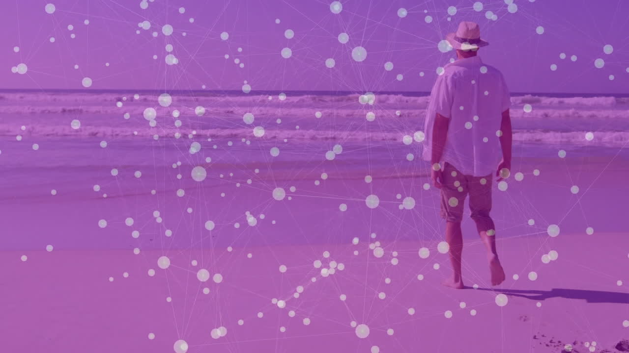 Man wearing straw hat standing on sandy beach facing ocean, displaying technology network overlay