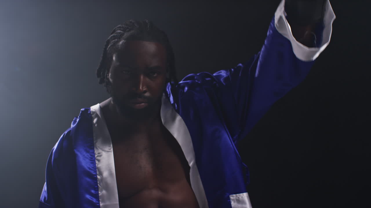 권투 경기가 시작되기 전에 링에 들어오는 권투 선수의 초상화. 권투 경기를 시작하기 전에 권투 선수가 무을 흔들고 팬들을 환영하고, 낮은 키 조명과 함께 장갑을 치고 있습니다.