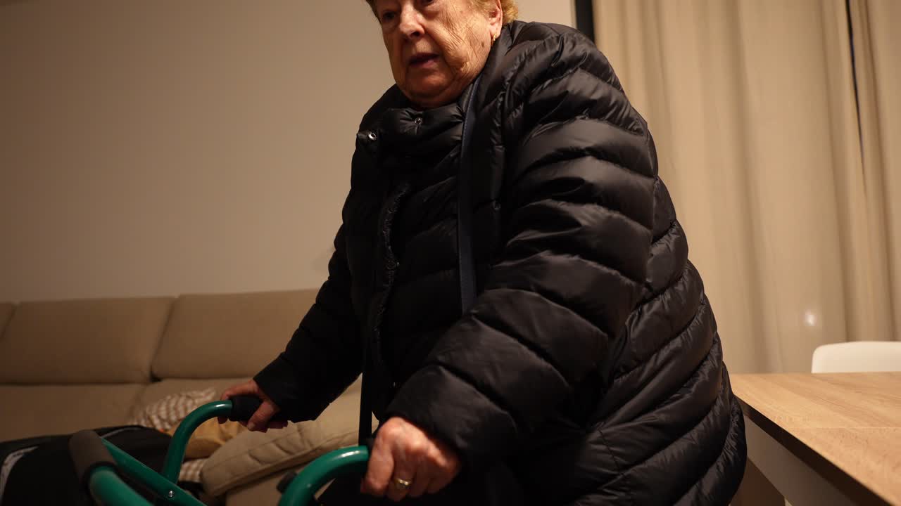 Elderly woman wearing a coat at home standing up with a walker