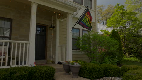 rainbow flag flying from front of house in the suburbs with a boom up the side of the house