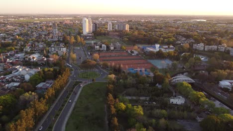 aerial flyover rural tigre city with traffic on road during sunset in argentina - small city near buenos aires with skyscraper