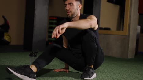 man drinking water have a rest after floor push ups at dark gym