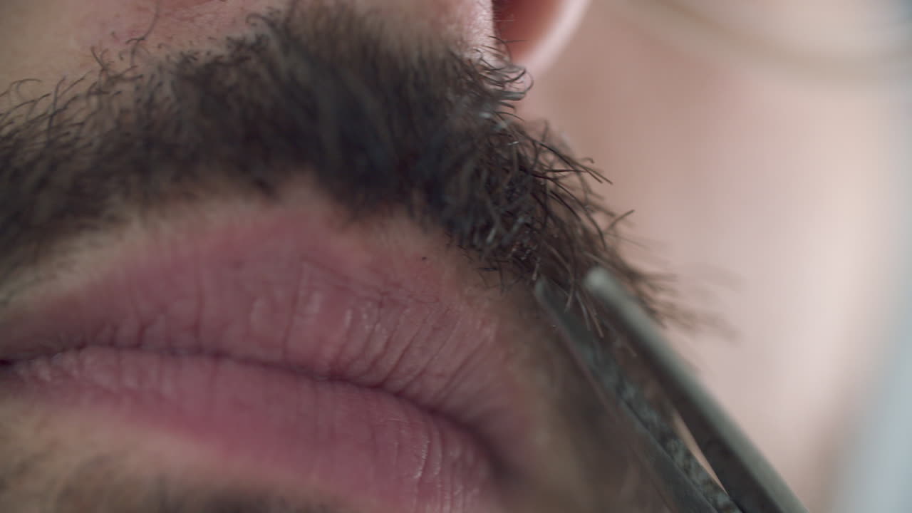 Man trimmar mustasch med skäggtrimmer.