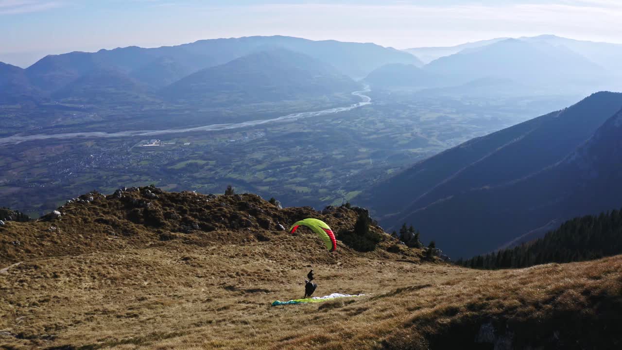 Mand med paraglider løber og svæver over Pizzocco-bjerget, adventuresport.