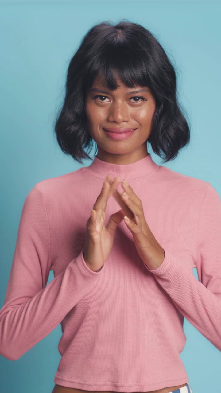 Mysterious southeast asian woman steepling hands and looking at camera on blue