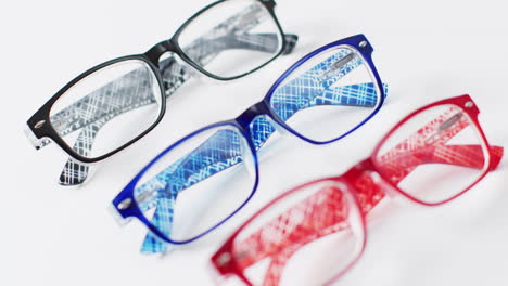 video of three coloured pairs of glasses on white background with rack focus