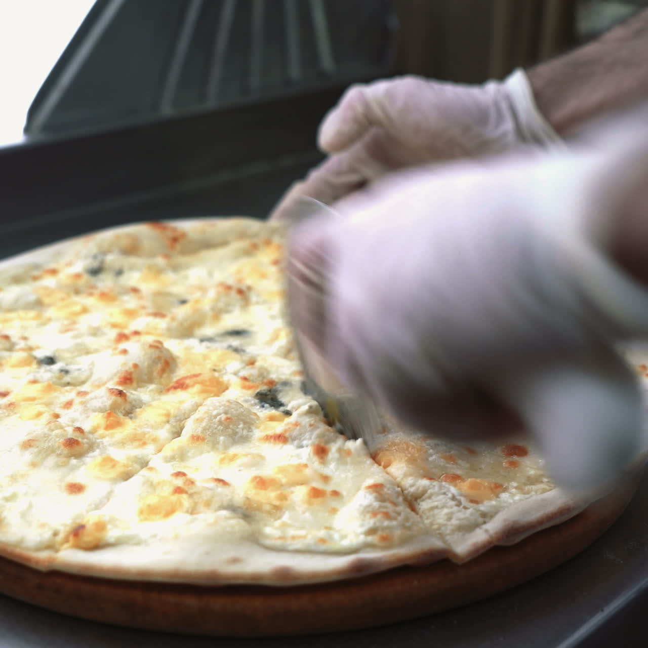 Cutting pizza on slices with special knife. Hand holding knife. Sqare video