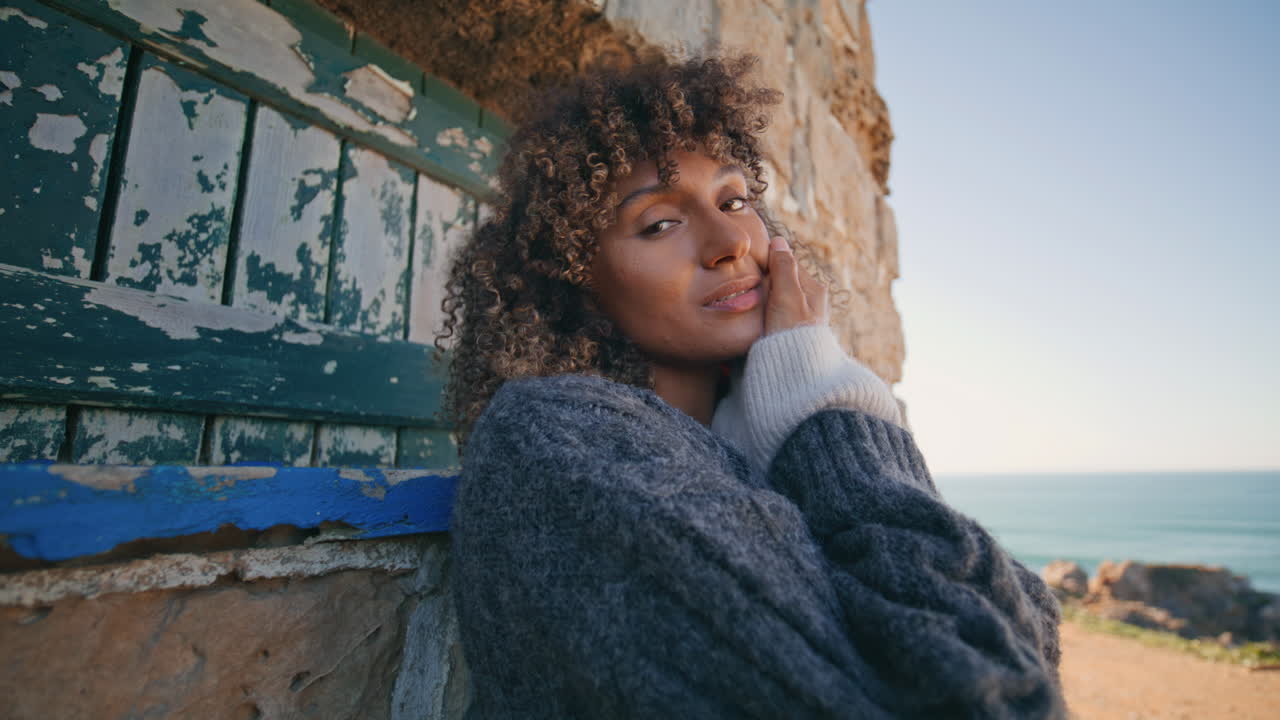 Yndig model smiler til kameraet, læner sig op ad slotsmur, portræt. Glad kvinde poserer.