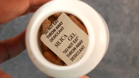 mano que sostiene un recipiente de desecante de gel de sílice
