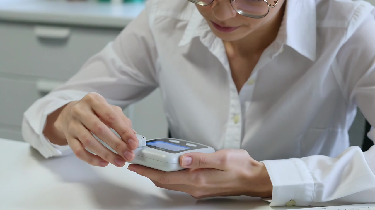 Donna che fissa un modulo su un dispositivo medico portatile al bancone della clinica, preparandolo per l'uso.