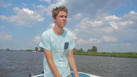 young man is sailing a electric sloop in the netherlands friesland in the summer in slowmotion