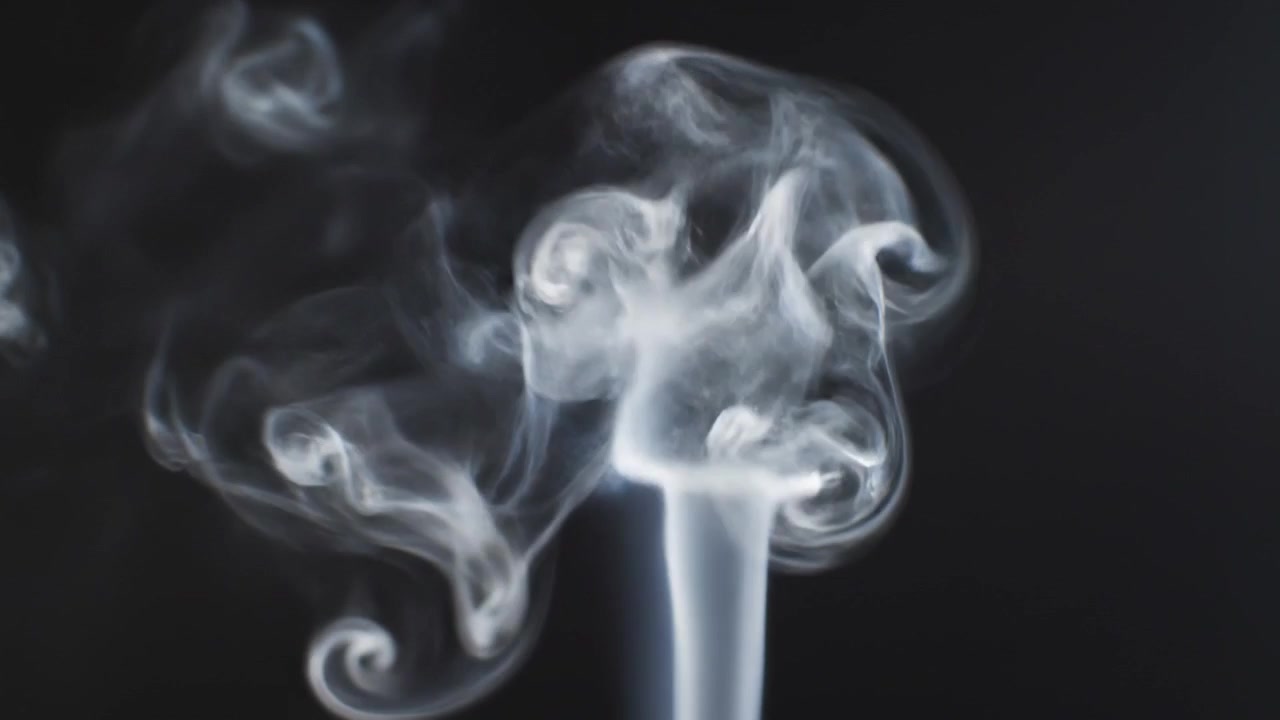 Fumo bianco leggero che sale a spirale su sfondo nero