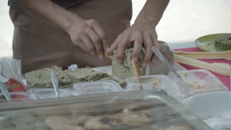 person preparing and cutting green paste on bread at a food stall