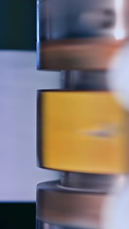diaper producing factory. shiny metal roller spinning around. blurred shaft at the backdrop. close up. vertical video