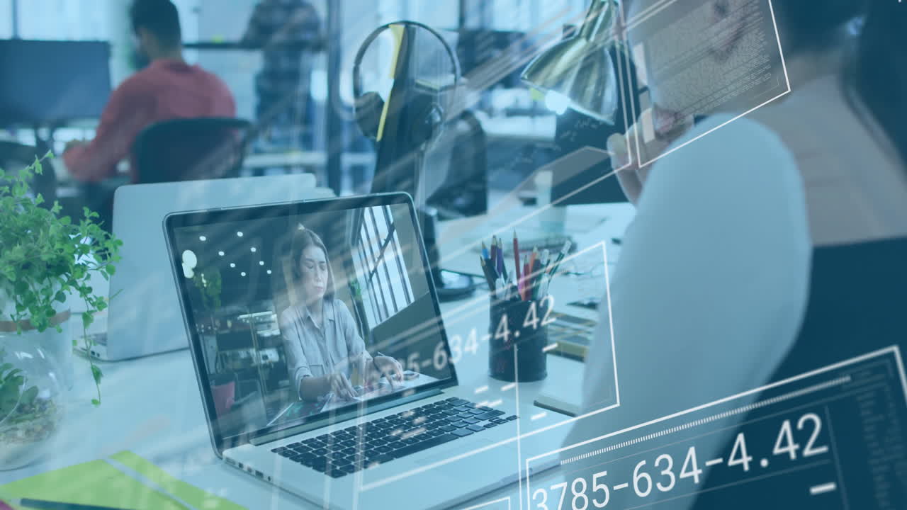Woman sitting at desk holding smartphone making business call in office with floating chart icons