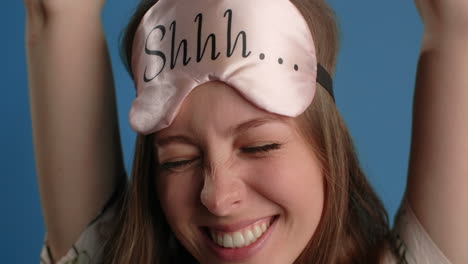 woman wearing sleep mask, stretching and smiling