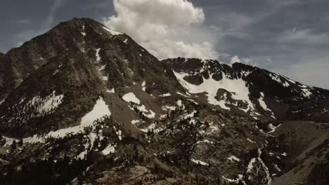 Filmische-Luftdrohnenaufnahmen-Eines-Schneebedeckten-Gipfels-Des-Yosemite-Nationalparks-Inmitten-Bewölktem-Himmel