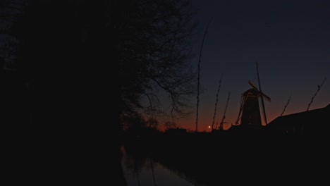 Wide-pan-of-beautiful-Dutch-landscape-at-magic-hour-with-a-historical-windmill-in-the-background