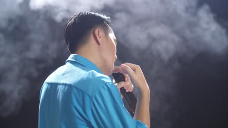 man singing on stage with smoke