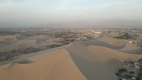 massive desert sand dunes tower high above hazy ice peru, aerial