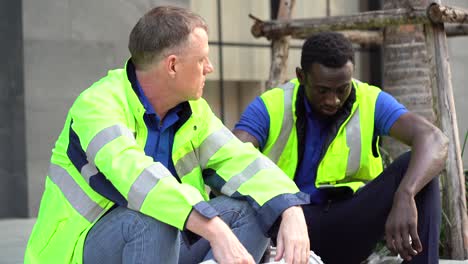 unhappy african american technician and senior engineer manager take a break sitting on street talking together having problems in work . fired from work . worker man stress from unemployed