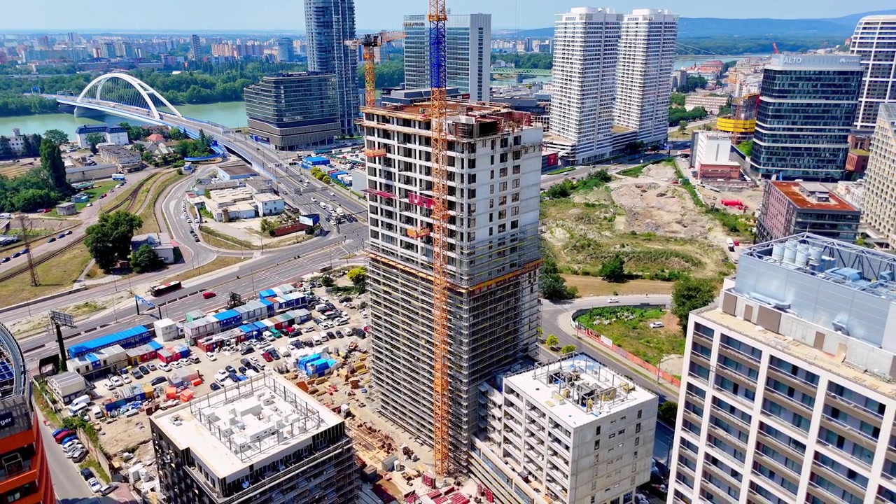 Bratislava, Slovacchia, 2 giugno 2026: Sviluppo urbano moderno, Bratislava, Slovacchia. Ripresa verticale con drone di un grattacielo in cemento in costruzione accanto a strade e un parcheggio.