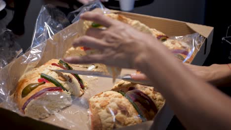 latina woman clutching a slice of a rosca de reyes and getting a baby jesus on the slice, on january 6 with her family due to three kings day celebration in mexican family home