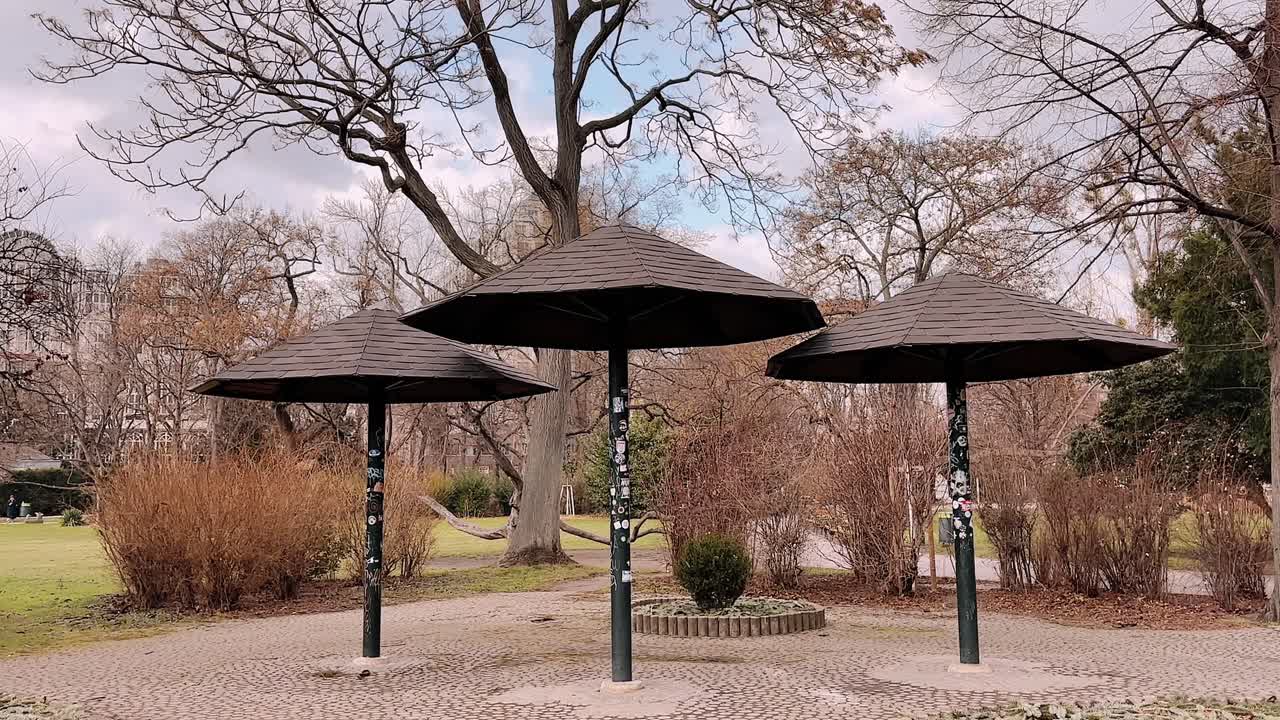 three street park umbrellas in vienna austria under cloudy sky with bare trees and autumn bushes