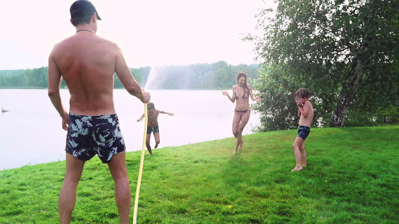 여름에 시골 집의 뒷마당에서 가족들이 물과 호스링으로 놀면서 휴식을 취합니다.