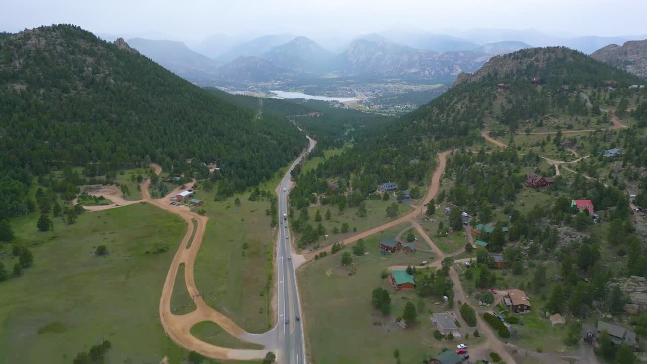 volando alto sobre una carretera entre campos verdes y montañas con autos que viajan en el campo de denver, colorado, ee.uu.