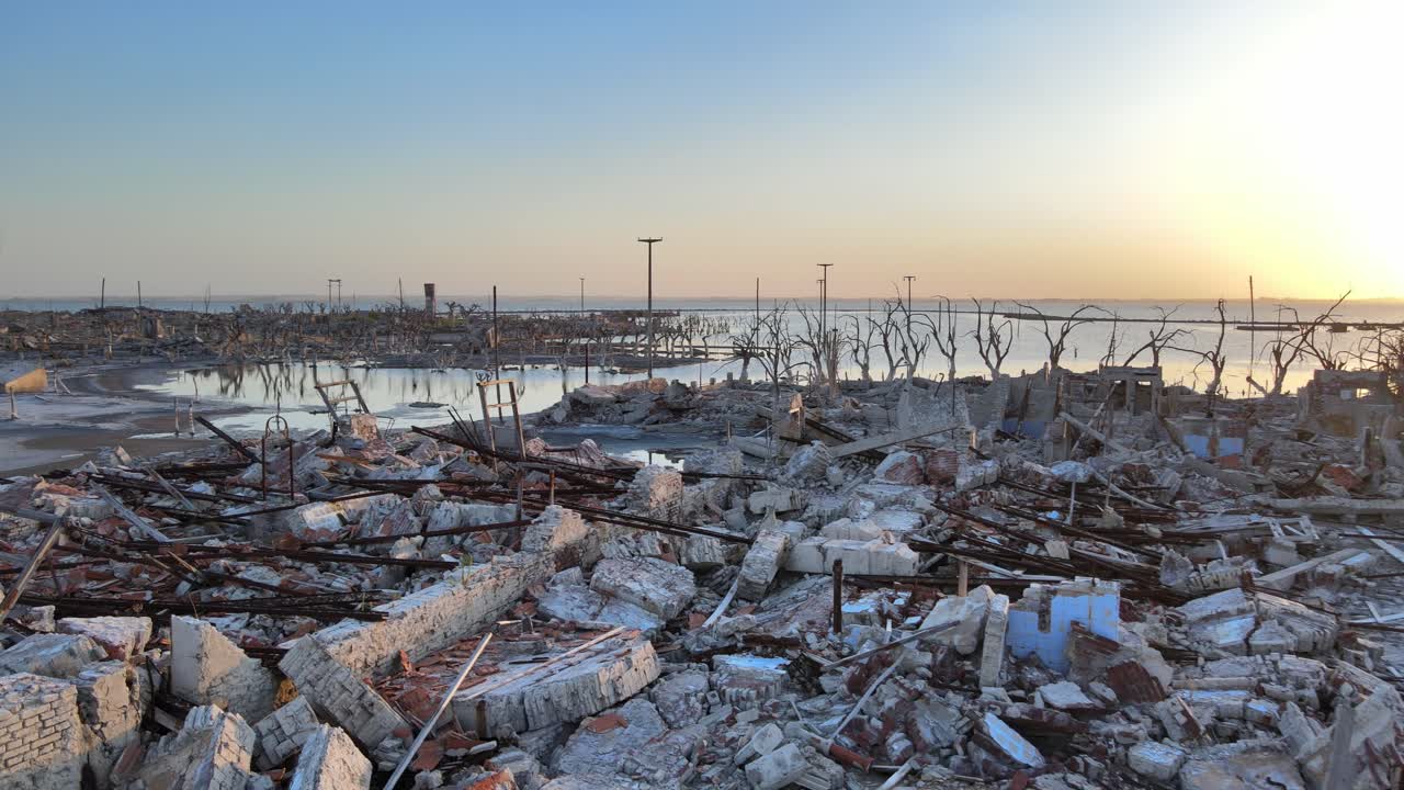 한때 번창했던 아르헨티나 스파 마을인 빌라 에페쿠엔을 포착한 느린 팬 샷, 부서진 폐허와 집 조각, 일몰 전망으로 마을을 쓸어버린 홍수
