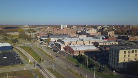 backward aerial of street traffic through muskegon, mi, urban area