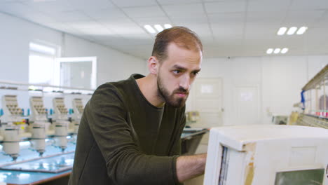 Young-man-introducing-data-on-sewing-computer