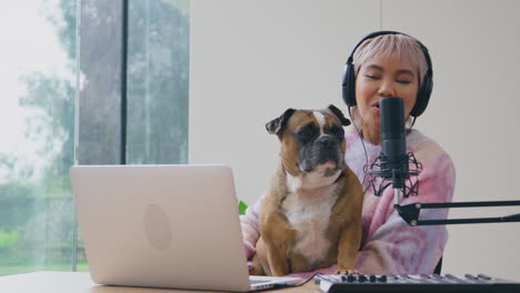 woman with pet french bulldog recording podcast or broadcasting on radio in studio at home