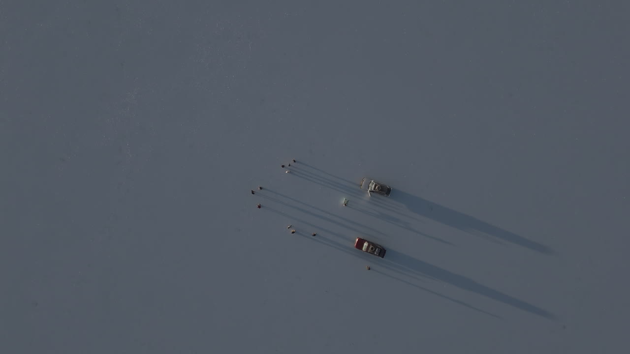 Top down drone shot flying over the salt flats in Uyuni Bolivia during sunset with shadows of people and a truck in the reflection of the water LOG