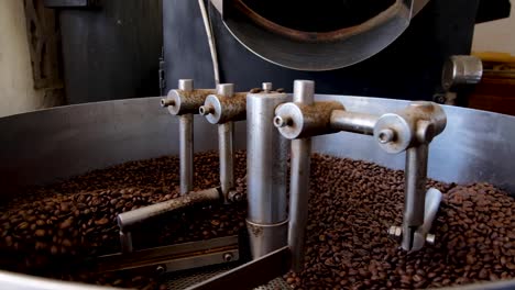 cierre de granos de café arábica recién tostados en una máquina tostadora de café industrial profesional, granos de café dorados de color marrón oscuro