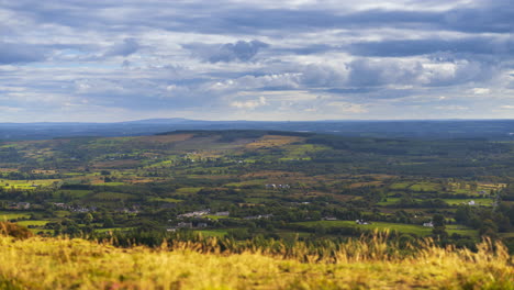 Lapso-De-Tiempo-De-Hierba-Borrosa-En-Primer-Plano-Y-Paisaje-Rural-A-Distancia-Durante-Un-Día-Nublado-Y-Soleado-Visto-Desde-Arriba-De-Lough-Meelagh-En-El-Condado-De-Roscommon-En-Irlanda