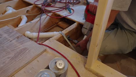 Plumber-drilling-through-floor-joists