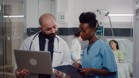 Enfermera-Africana-Y-Médico-Cirujano-Con-Uniforme-Médico-Analizando-Los-Síntomas-De-La-Enfermedad