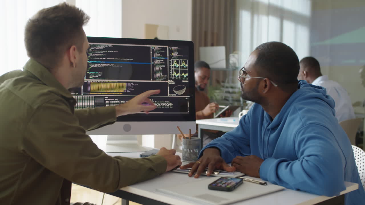 Experienced Programmer Showing Coding Script on PC to Male Newcomer at Office